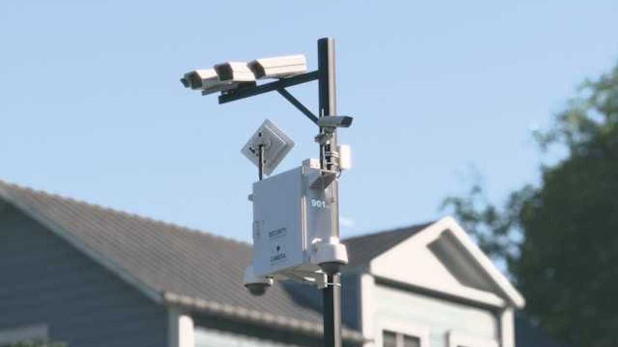 Cameras mounted on a tall pole with a house in the background