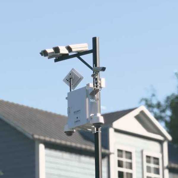 Cameras mounted on a tall pole with a house in the background