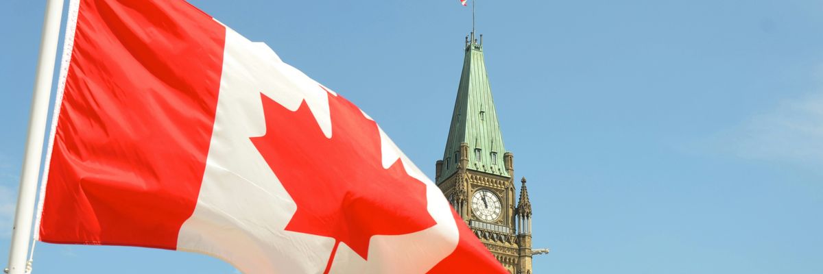 Canadian flag on a sunny day waving in front of the Canadian parliament building