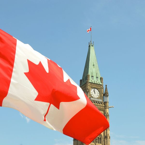 Canadian flag on a sunny day waving in front of the Canadian parliament building