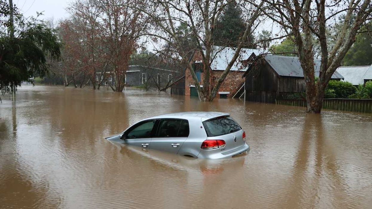 Car bobbing in brown floodwaters on flooded street in flooded neighborhood