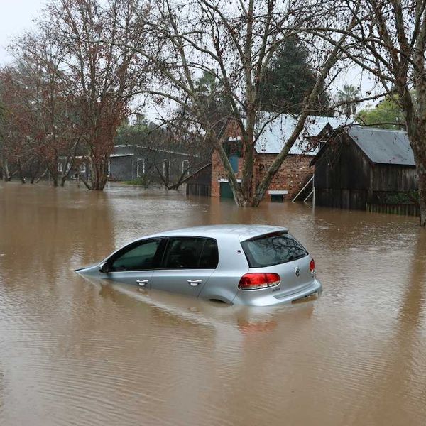 Car bobbing in brown floodwaters on flooded street in flooded neighborhood