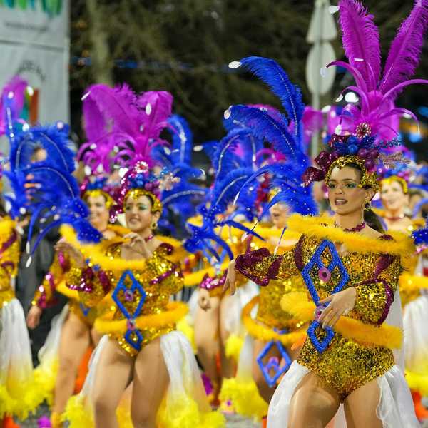 Carnival dancers parade in vibrant costumes.