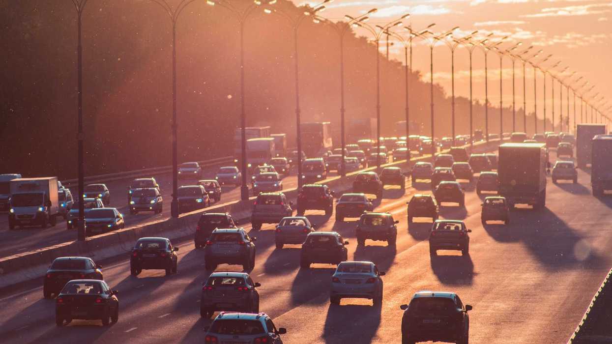 cars on busy freeway passing through in late afternoon sun.