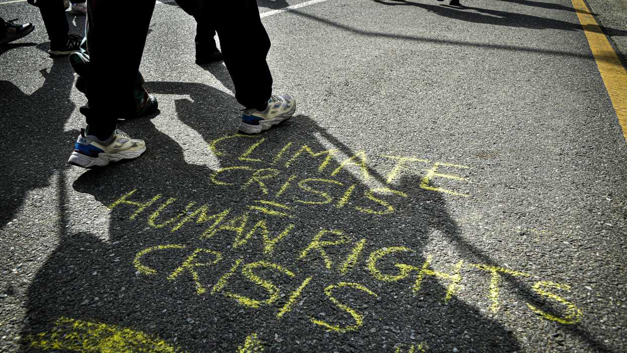 Chalk on the pavement saying Climate Crisis equals Human Rights Crisis.