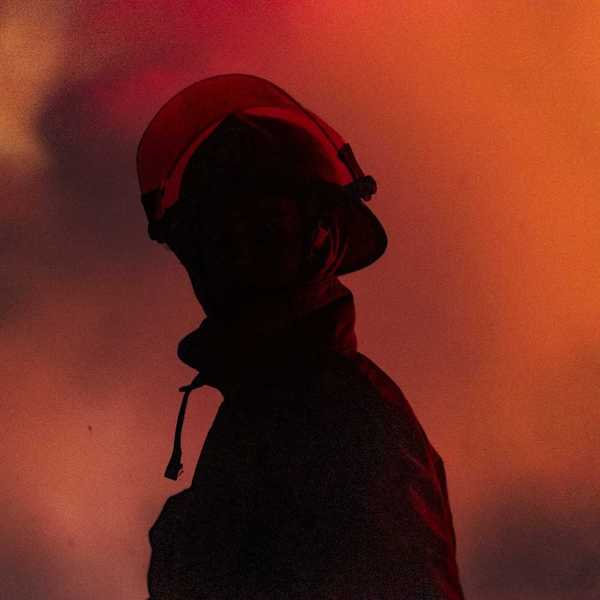 Chest-up view of firefighter in profile with mostly obscured face, faced towards the camera