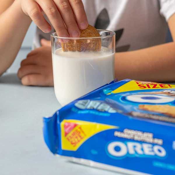 Child dunking an Oreo cookie into a glass of milk prior to eating