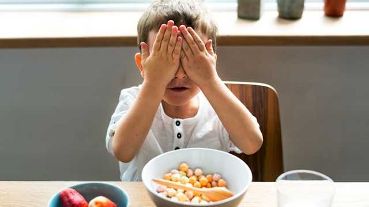 Child sitting at a table in front of a bowl of cereal