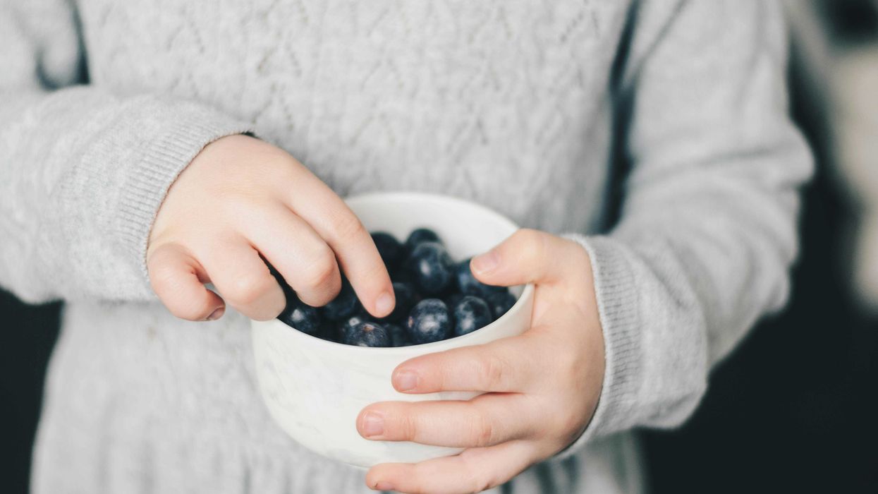 Child taking blueberries out of a bowl