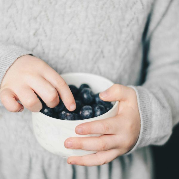 Child taking blueberries out of a bowl