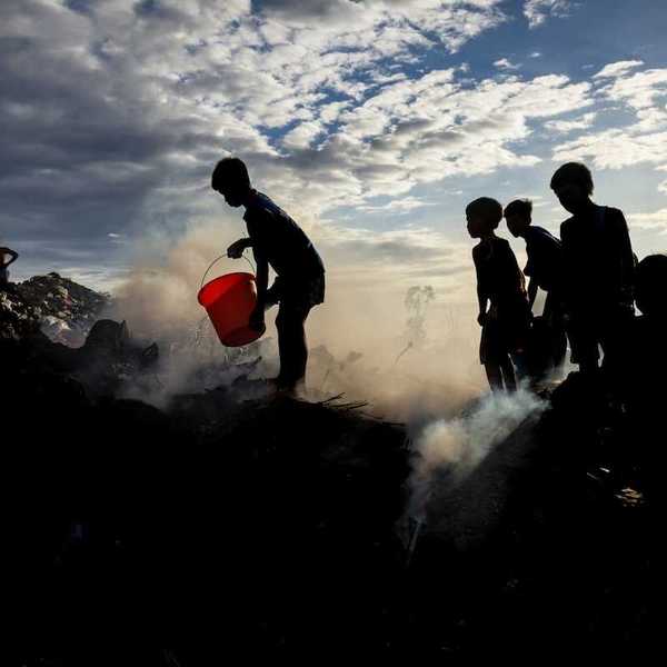 Child trash pickers on top of a smoking, smoldering, trash mountain.