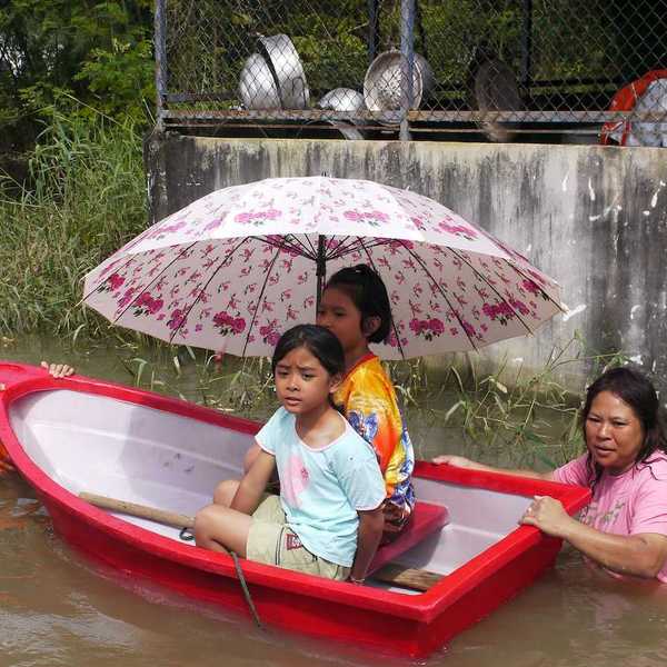 Children being transported through deep water in a small plastic dinghy during the monsoon flooding of October 24 2010 in Nakhon Ratchasima Thailand.