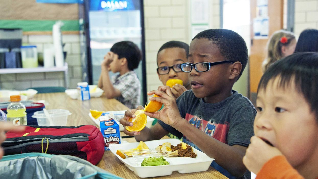 Children eating school lunches at a cafeteria table.