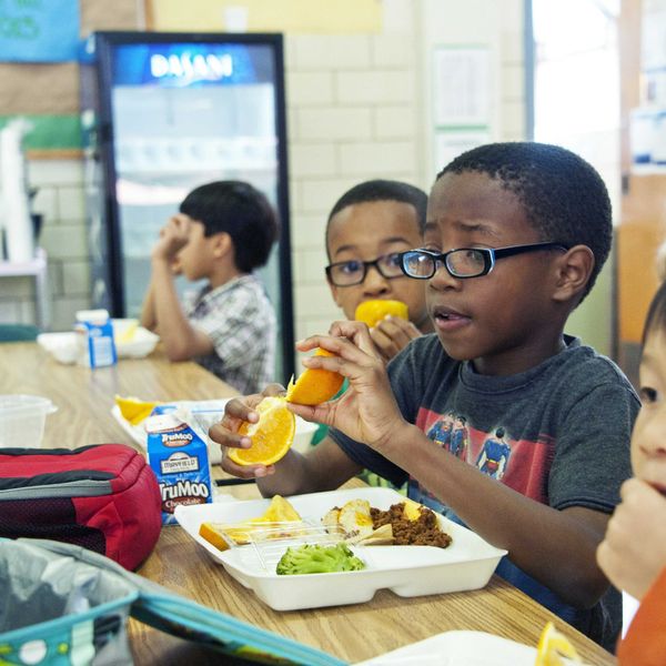 Children eating school lunches at a cafeteria table.