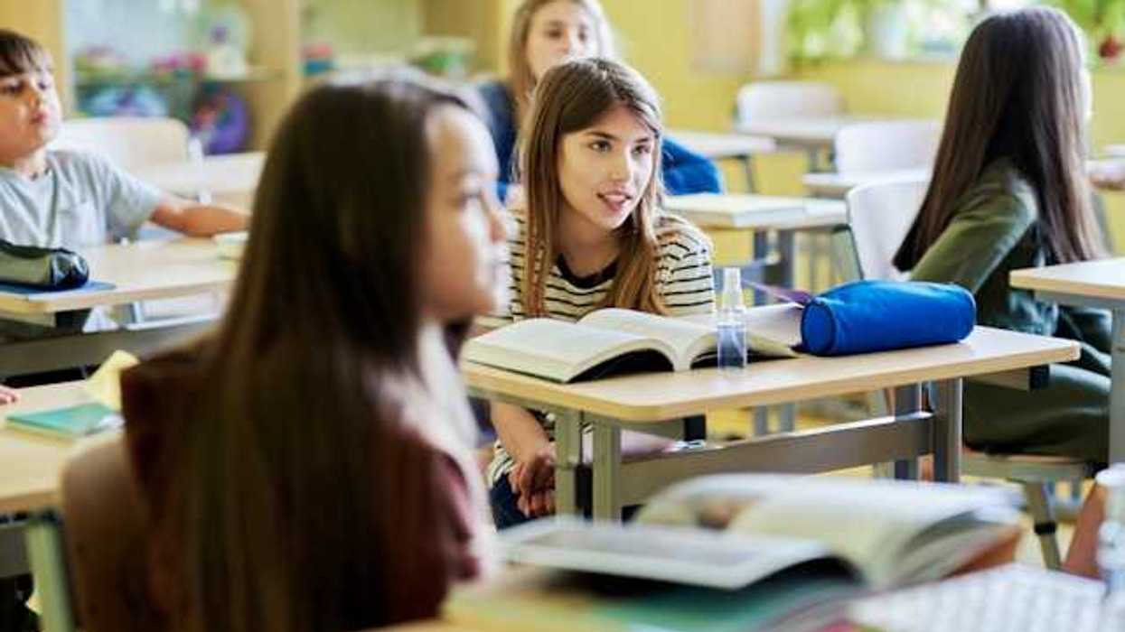 Children sitting in a classroom with books on their desks