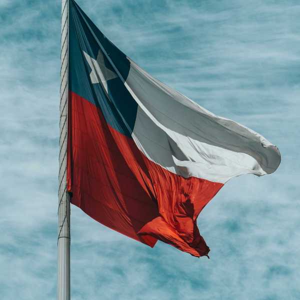 Chilean flag waving against a cloudy blue sky.