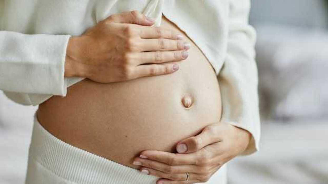 Closeup of a young pregnant woman touching her belly