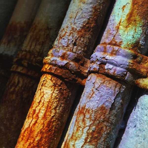 Closeup of old rusty, corroded pipes fastened to concrete surface