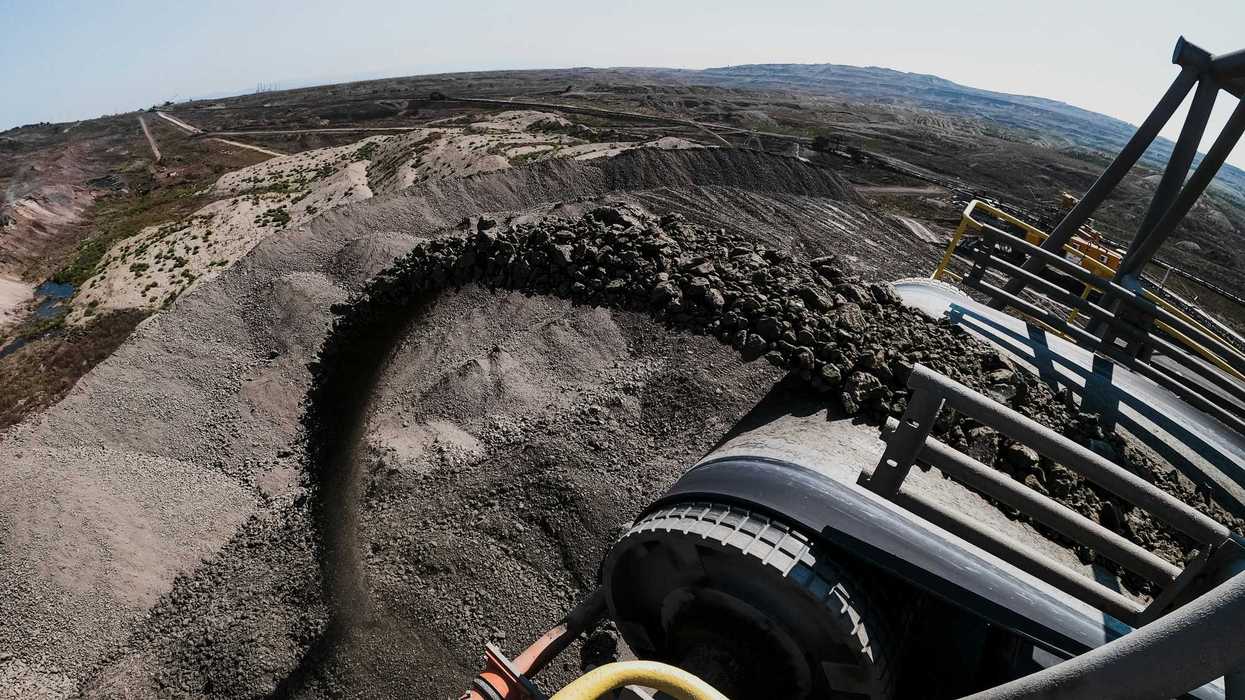 Coal flowing out of a machine in an open pit mine.