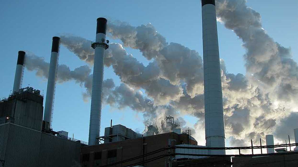 Coal plant with four smokestacks emitting pollution.