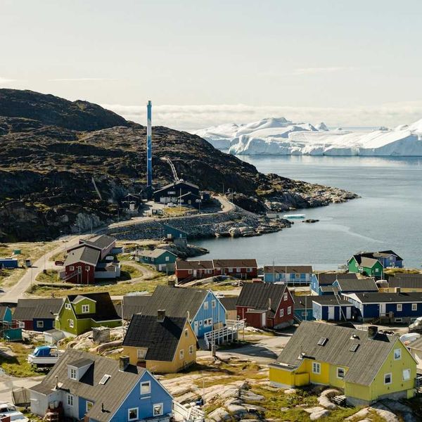 Coastal village in Greenland with multicolored homes and ice floes in the background