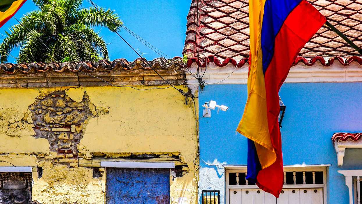 Colombian flag hanging from a building with colorful tiled buildings in background.