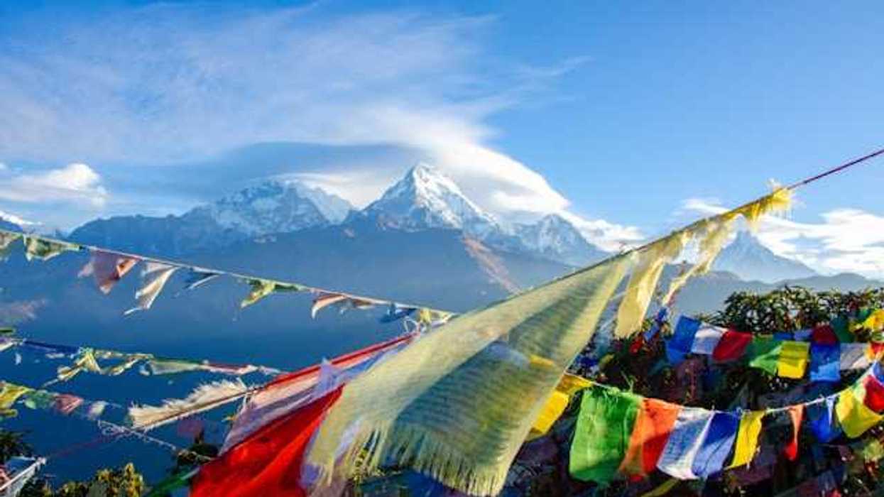 Colorful banners strung across a valley with snow-covered mountains in the background