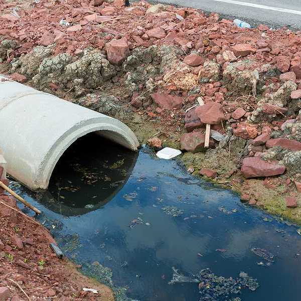 Concrete circular run-off pipe discharging water and/or sewage pipe polluting a river.
