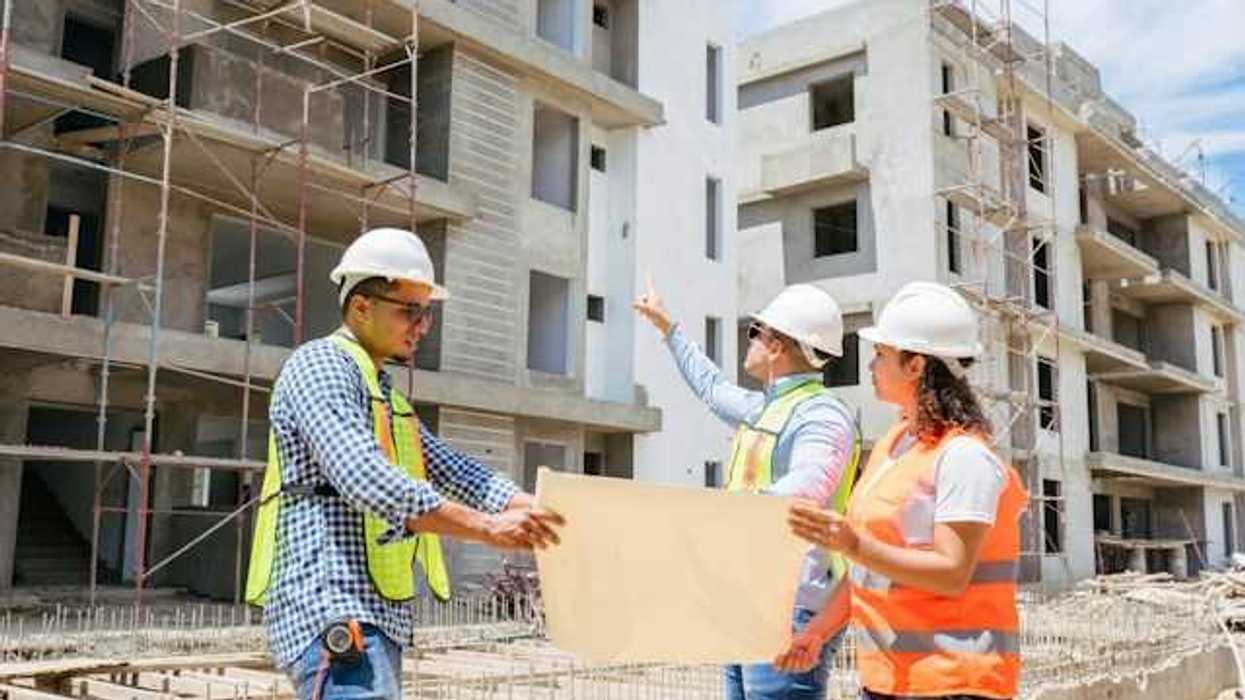 Construction managers looking at plans while viewing concrete buildings under construction
