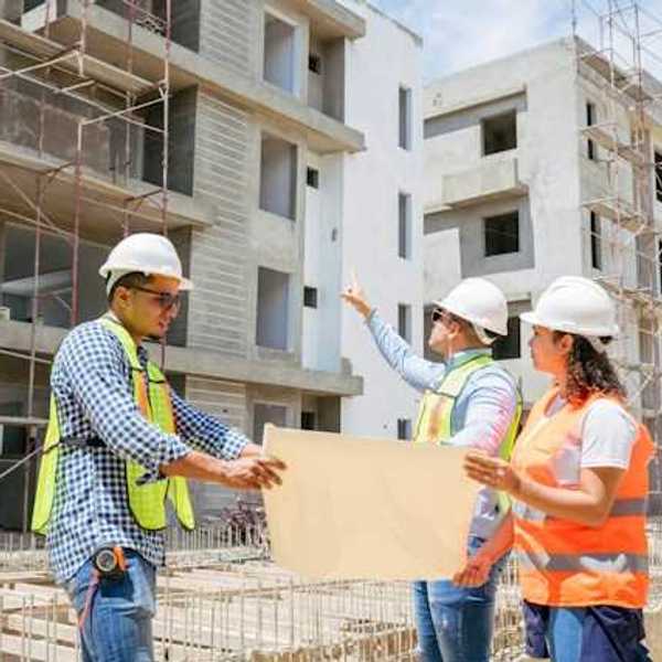 Construction managers looking at plans while viewing concrete buildings under construction