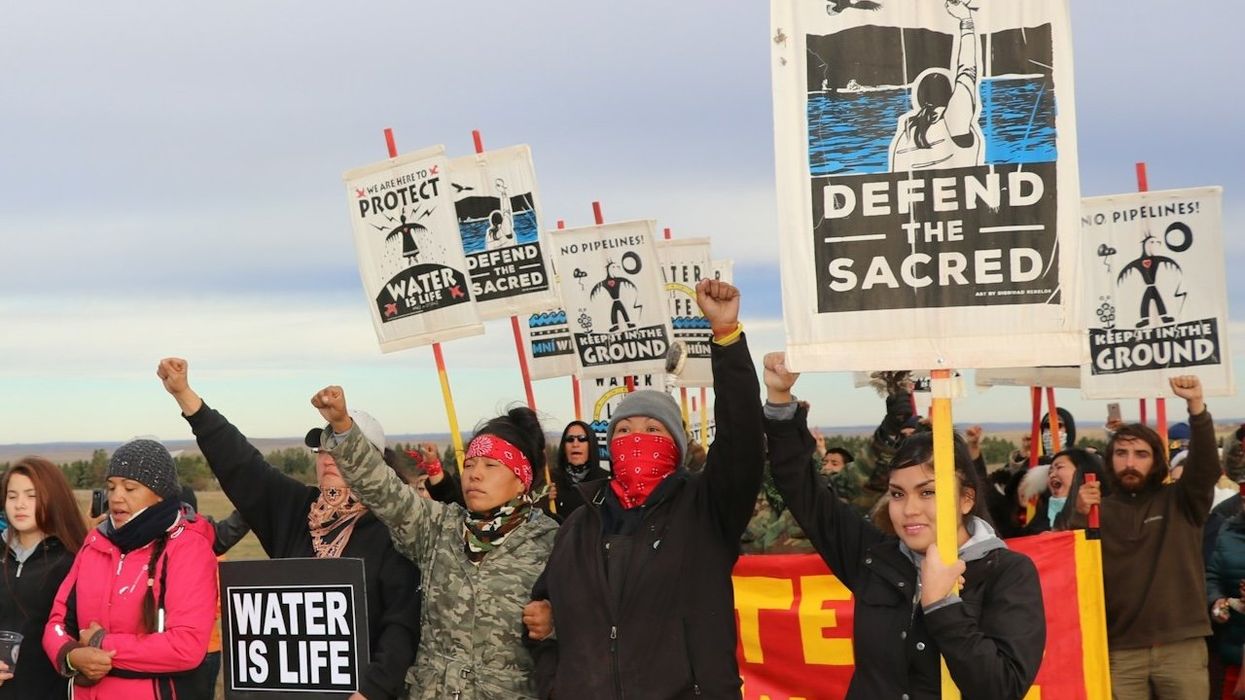 Dakota Access Pipeline protesters hold signs  and raise fists.