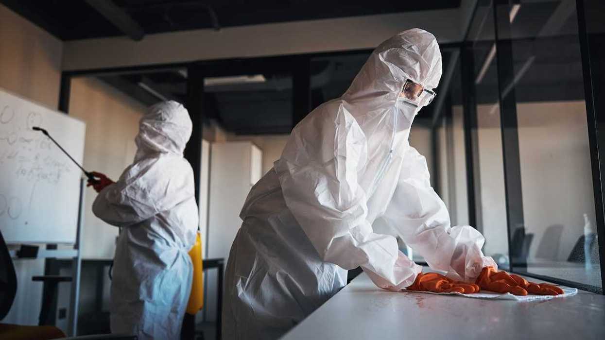 Decontamination being carried out by workers in HazMat suits.