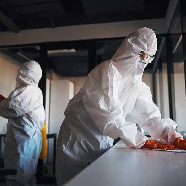 Decontamination being carried out by workers in HazMat suits.