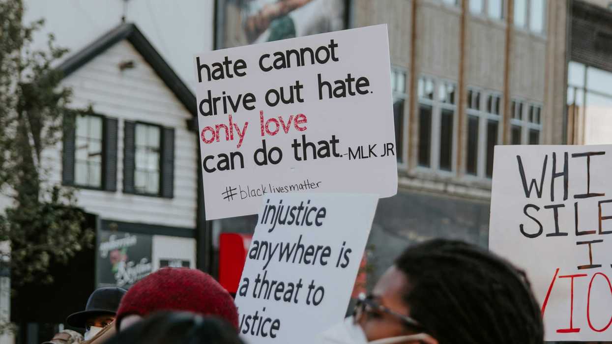 Demonstrators hold signs calling for racial justice.
