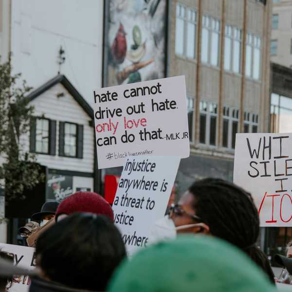 Demonstrators hold signs calling for racial justice.