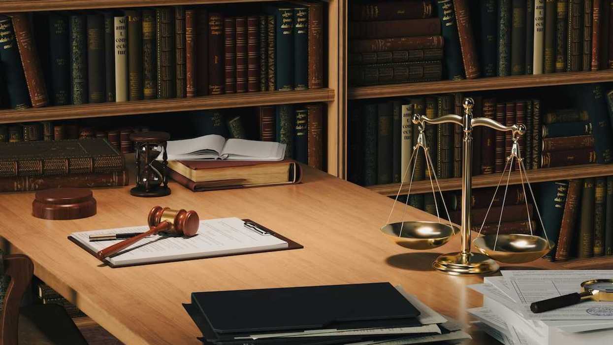 Desktop containing legal paperwork, gavel and scales representing justice