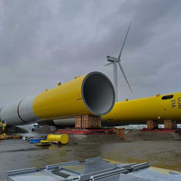 Dismantled yellow and white wind tower lying on the ground awaiting assembly