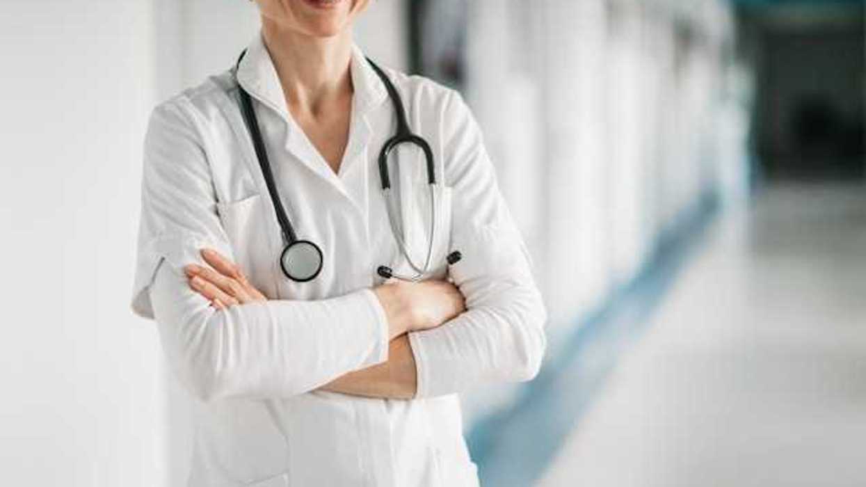 Doctor standing with her arms crossed and smiling in a hospital hallway