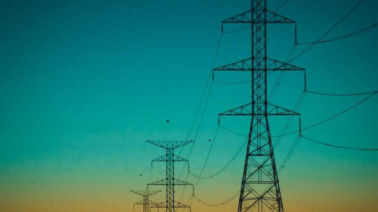 Electrical transmission lines against a rainbow-colored sky