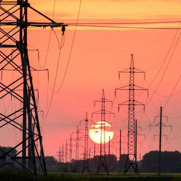 Electrical transmission lines silhouetted against setting sun