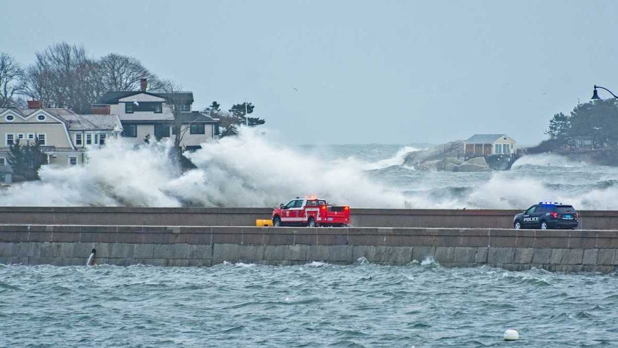 Emergency vehicles — pickup truck and police vehicle traveling amidst with storm-whipped surf