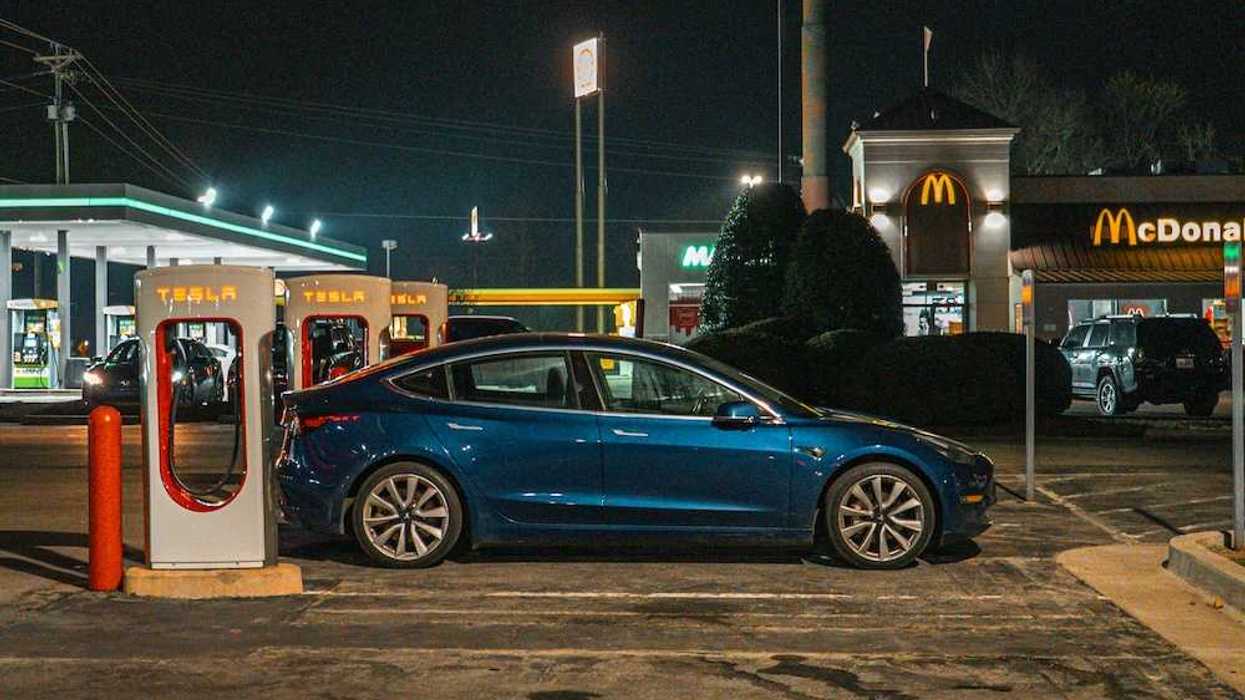 EV parked at a Tesla charging station adjacent to a MacDonald's restaurant