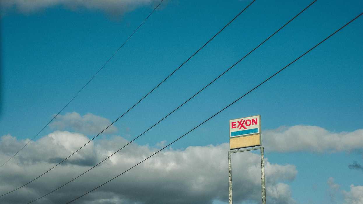 Exxon sign against blue sky marked with power lines during daytime.