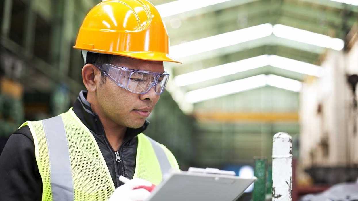 Factory worker writing on a clipboard while checking work