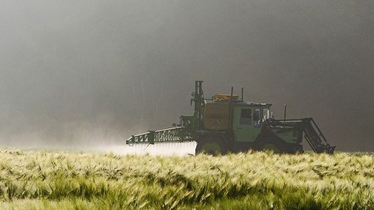 Farm equipment spraying pesticides on an agricultural field.