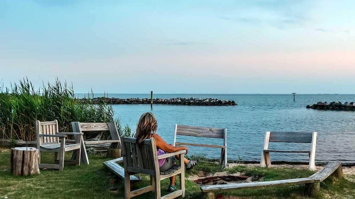 Female relaxing in a chair on a Chesapeake Bay beach watching a sunset.