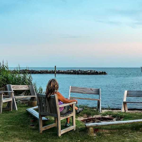 Female relaxing in a chair on a Chesapeake Bay beach watching a sunset.