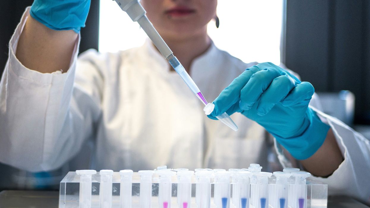 Female scientist in white lab coat putting samples into test tubes.