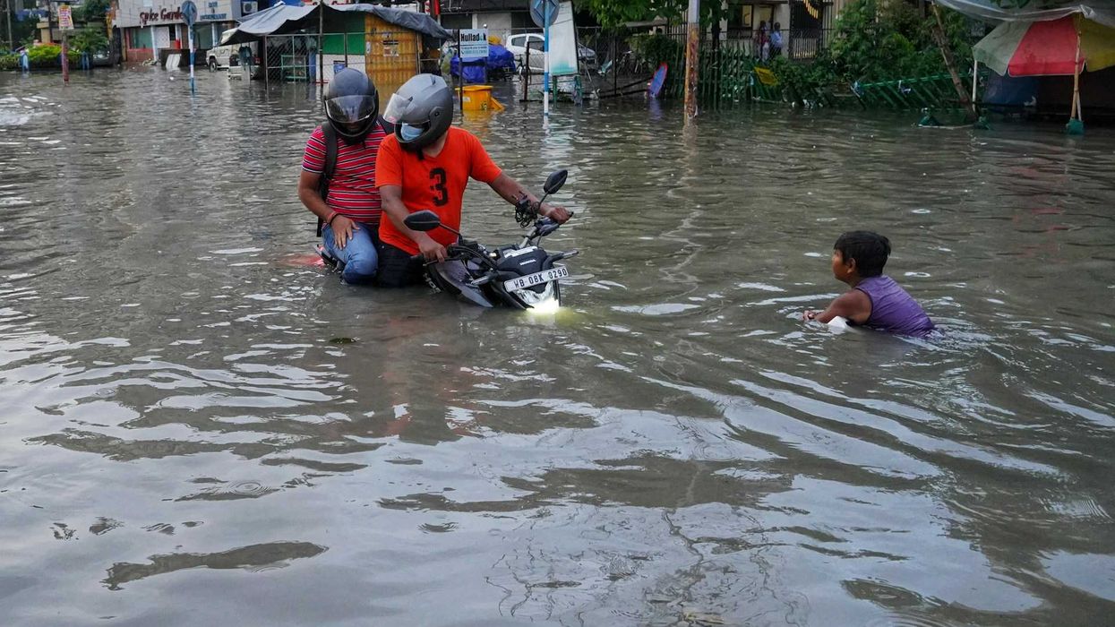 Filipinos navigating flooded street on motorcycle