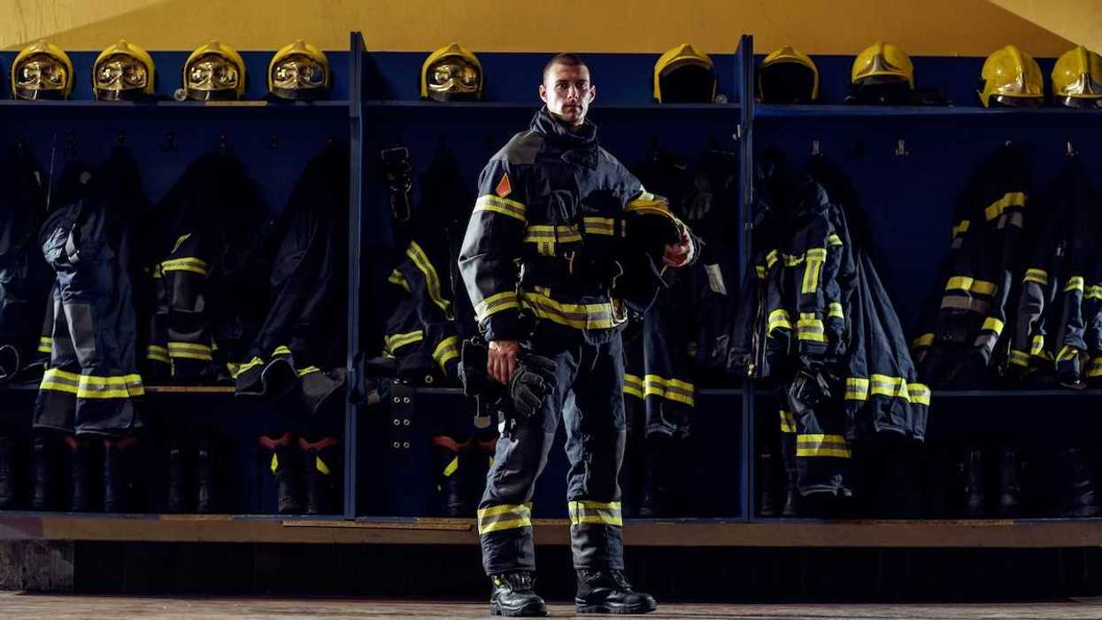 Firefighter clad in turnout gear standing in front of gear cubbies